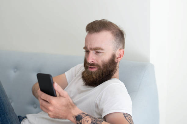 istock Puzzled frowning bearded guy resting on couch 1084353898