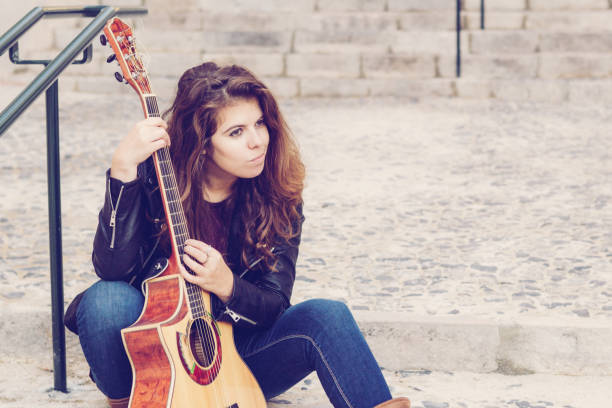 istock Cheerful female street performer testing guitar sound 1084356614