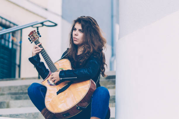 istock Pensive female guitarist testing new instrument 1084356646
