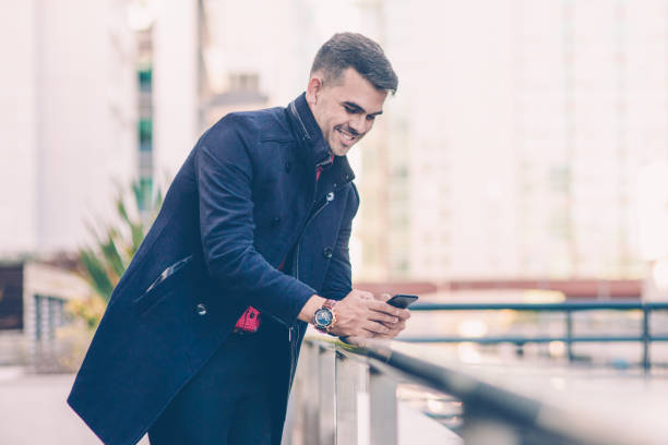 istock Cheerful handsome Hispanic man smsing on smartphone 1084356976