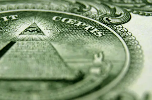Shallow focus on the eye of providence, above the pyramid, from the USA coat of arms, on the American one dollar bill.