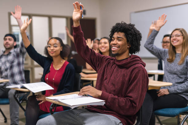 istock Black male college student raising his hand to answer a question during class 1084365062