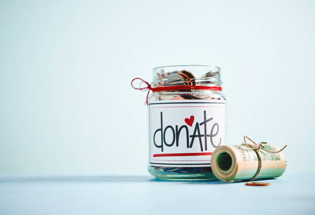 istock Money jar filled with coins and bills with bright blue background 1084367222