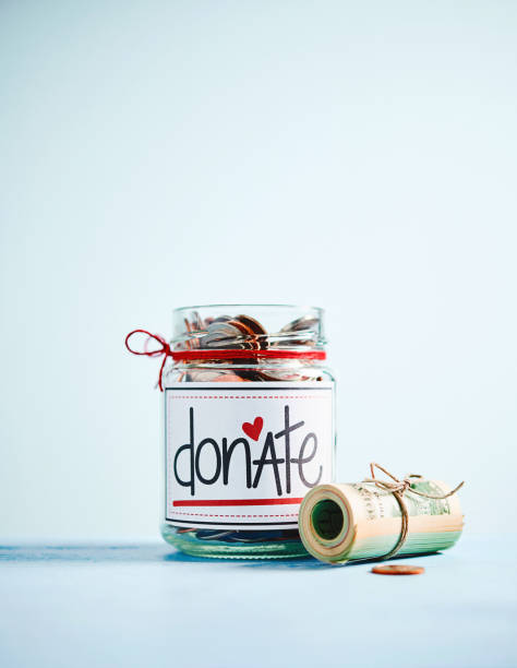 istock Money jar filled with coins and bills with bright blue background 1084367232