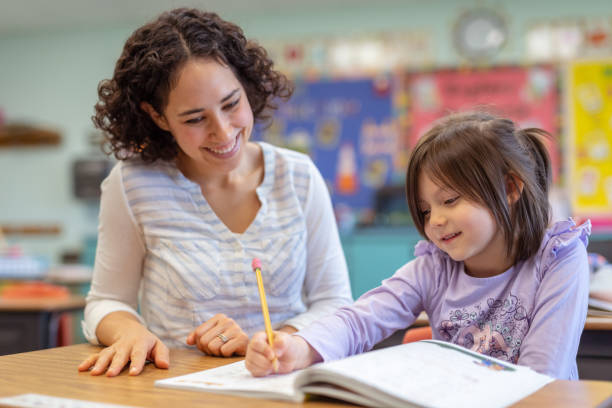 istock First grade girl talking with her teacher in the classroom 1084370752