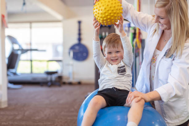 физиотерапевт, работающий с маленьким мальчиком в клинике - child therapy стоковые фото и изображения