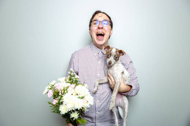 Nerdy Guy and Lap Dog Nerdy guy holding a lap dog and flowers because guys with puppy dogs get ladies. ugly dog stock pictures, royalty-free photos & images