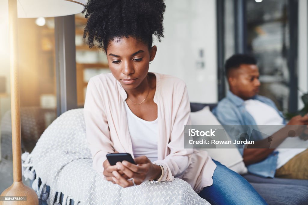Growing more and more disconnected Shot of a young couple using their mobile phones on the sofa at home Couple - Relationship Stock Photo