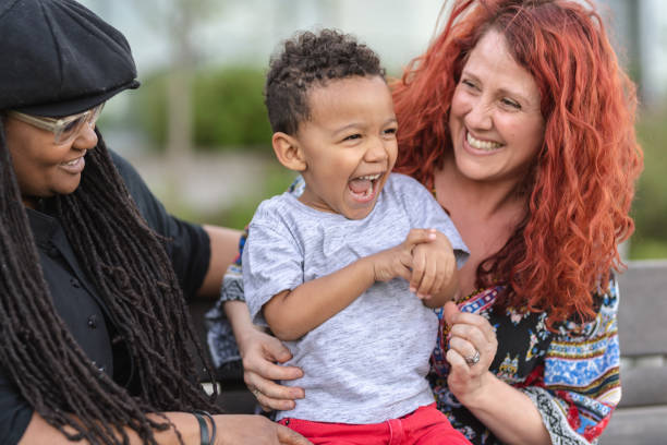 deux mères tenant leur fils sur leurs tours à l’extérieur dans le parc - couple black american culture kissing photos et images de collection