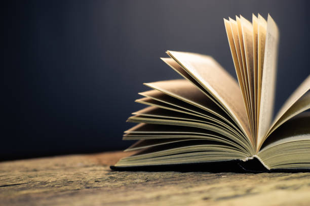 istock Open old book on a oak wooden table background of school board 1084399656