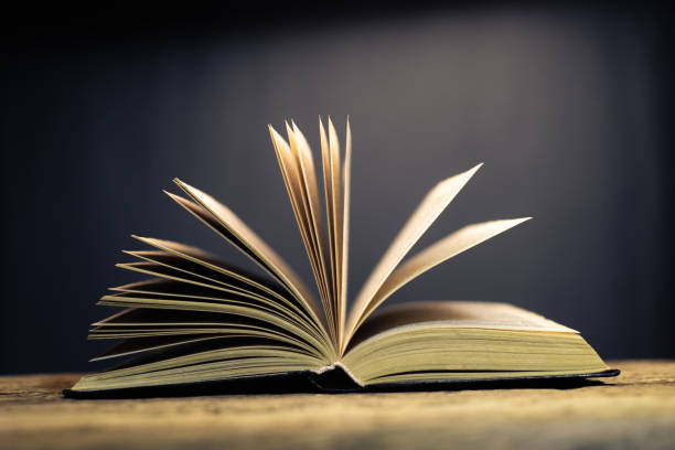 istock Open old book on a oak wooden table background of school board 1084399766