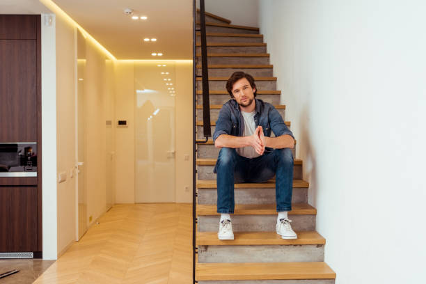 istock handsome man sitting on stairs and looking at camera 1084408956
