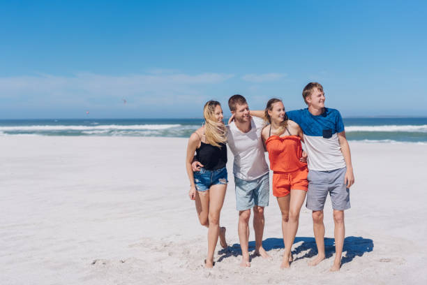 istock Four young friends looking down a sandy beach 1084415284