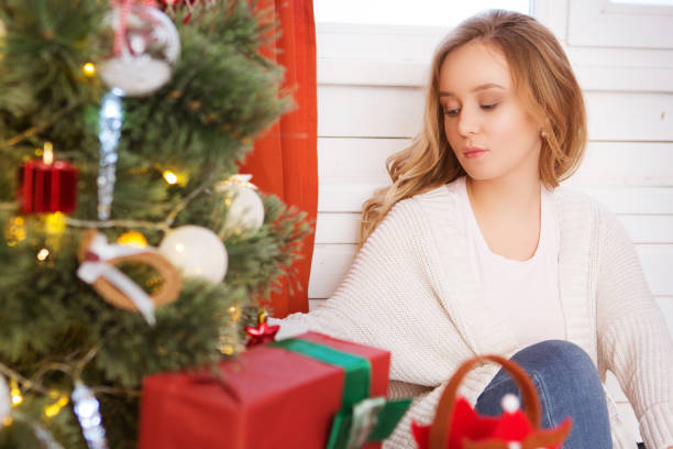 istock Young girl with christmas tree over window at home 1084417570