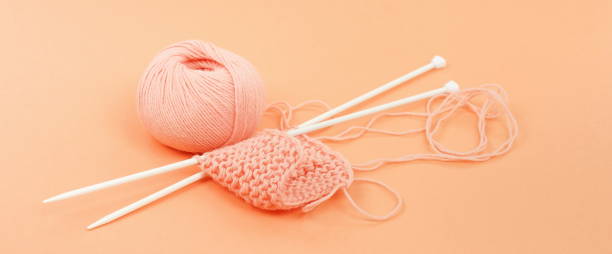 istock Banner knitting wool and knittig needles on coral color background 1084417948