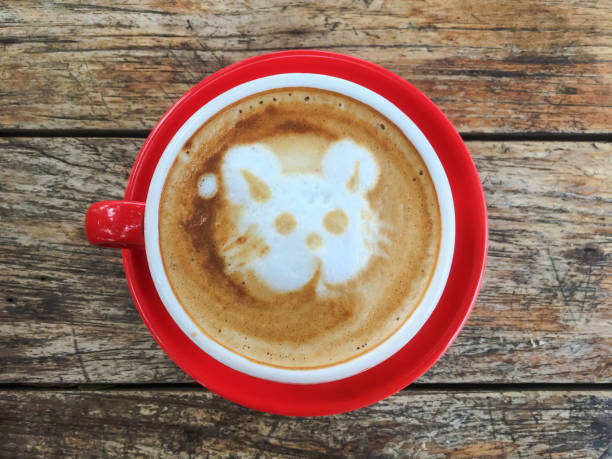 Close up hot cappuccino with a cute froth art, with a wooden background
