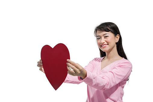 Pretty asian woman holding red heart posing isolated over white background. Valentines day