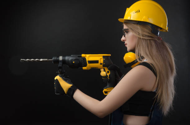 istock girl in construction clothes and protective equipment posing with a hammer 1084423602