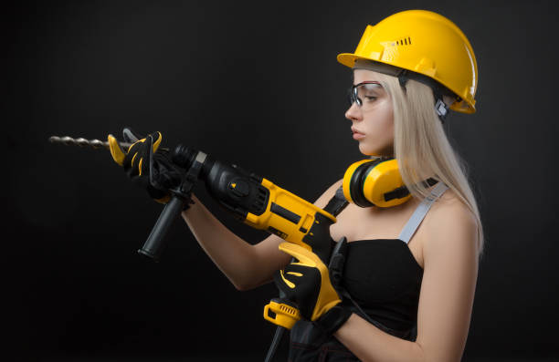 istock girl in construction clothes and protective equipment posing with a hammer 1084423616
