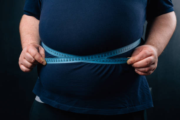 istock Fat man with a big belly on a dark background. Diet. 1084428650