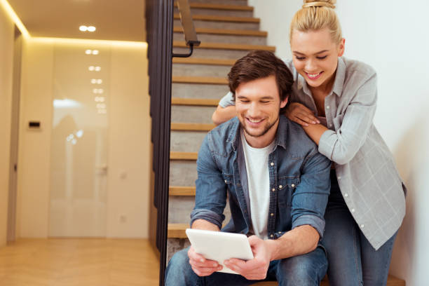 istock smiling family couple sitting on stairs and using digital tablet 1084435580