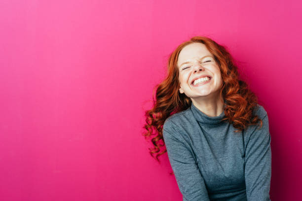 joven riendo mujer contra fondo rosado - vertical studio shot indoors pink fotografías e imágenes de stock