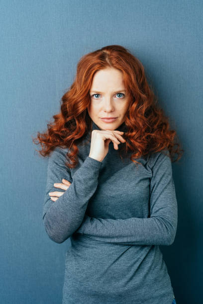 istock Young red-haired serious woman against blue wall 1084440672