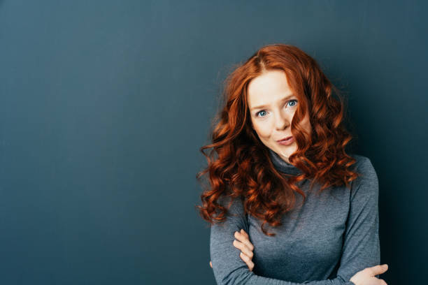 istock Young red-haired woman against dark background 1084440768