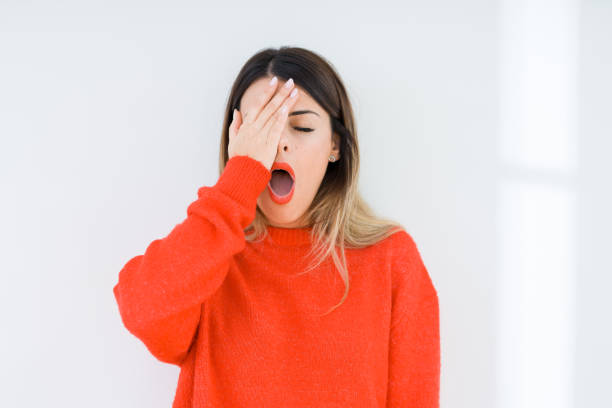 Young woman wearing casual red sweater over isolated background Yawning tired covering half face, eye and mouth with hand. Face hurts in pain. Young woman wearing casual red sweater over isolated background Yawning tired covering half face, eye and mouth with hand. Face hurts in pain. yawning stock pictures, royalty-free photos & images