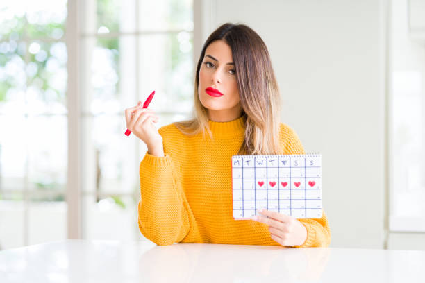 istock Young beautiful woman holding menstruation calendar at home with a confident expression on smart face thinking serious 1084445302