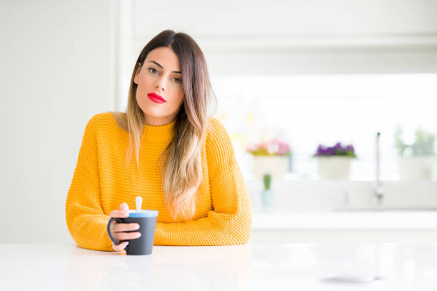 istock Young beautiful woman drinking a cup of coffee at home with a confident expression on smart face thinking serious 1084445450