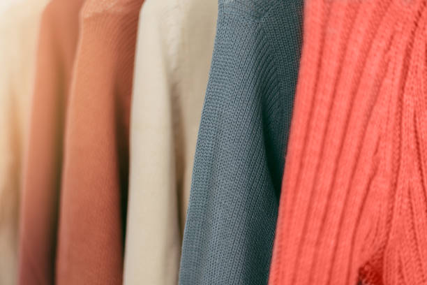 istock Pastel orange and coral knitted warm sweaters on white hangers. 1084448264
