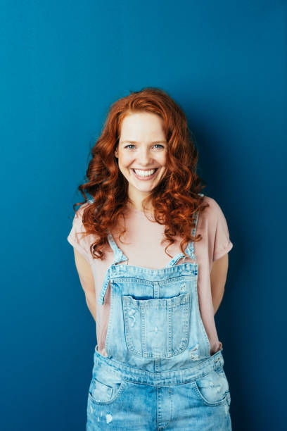 happy cheerful young redhead woman in dungarees - beautiful red hair curly hair human hair imagens e fotografias de stock