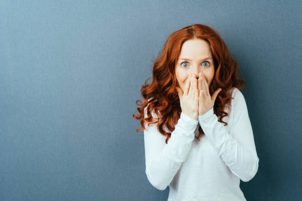Excited young redhead woman staring at camera stock photo