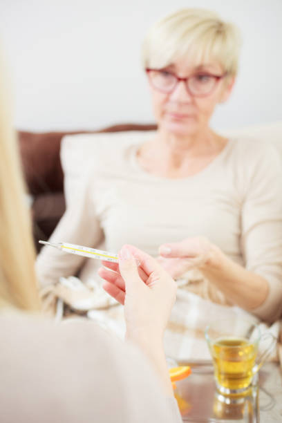istock Daughter checking her senior mother's temperature with a thermomete 1084456234