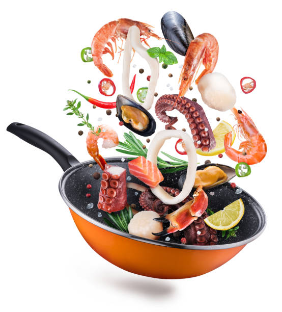 istock Flying seafood with spices falling into a frying pan. 1084458256