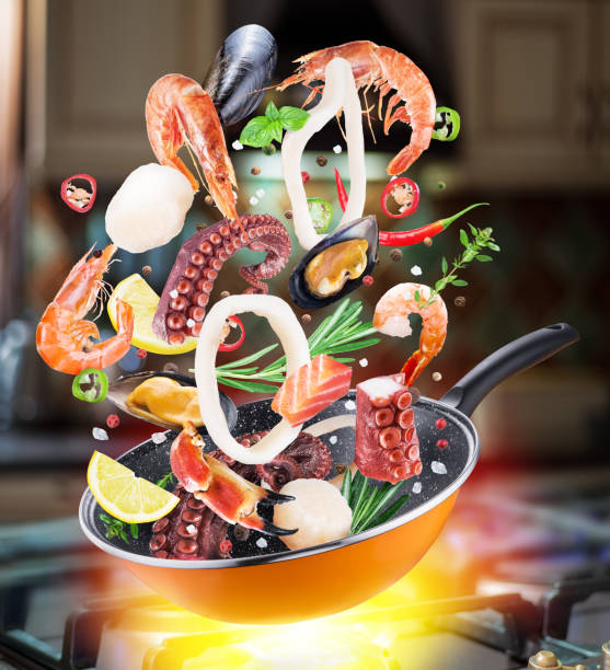 istock Flying seafood and spices falling into a frying pan. 1084458410