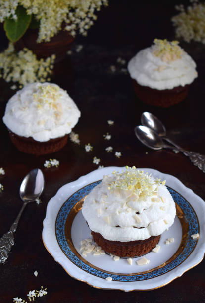 istock Chocolate capcakes with vanilla cream sprinkled with white chocolate and elderberry flowers. Vintage style. Copy space 1084459492