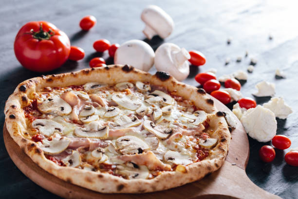istock Pizza with ham, mushrooms and mozzarella on wooden board. 1084462540