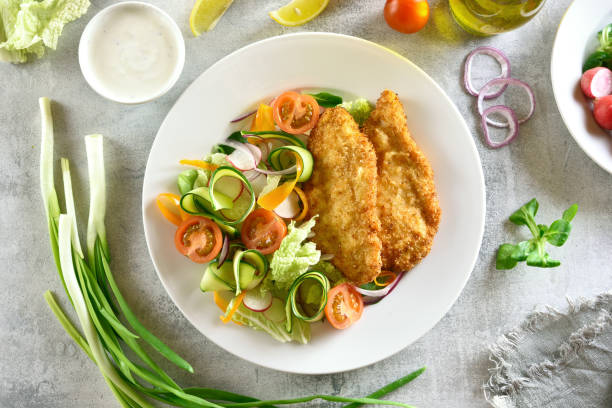 istock Vegetable salad and breaded chicken breast 1084464380