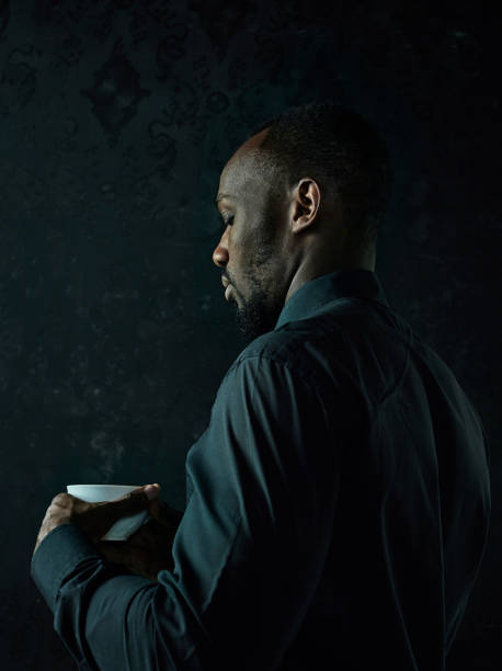 istock Stylish young black man with cup of coffee posing on dark background. 1084464528