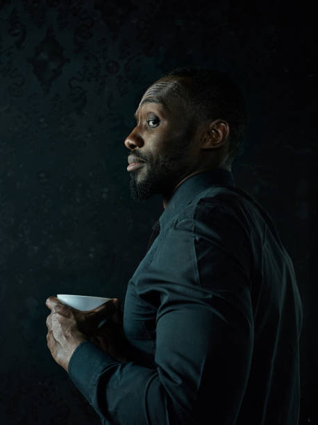 istock Stylish young black man with cup of coffee posing on dark background. 1084464564