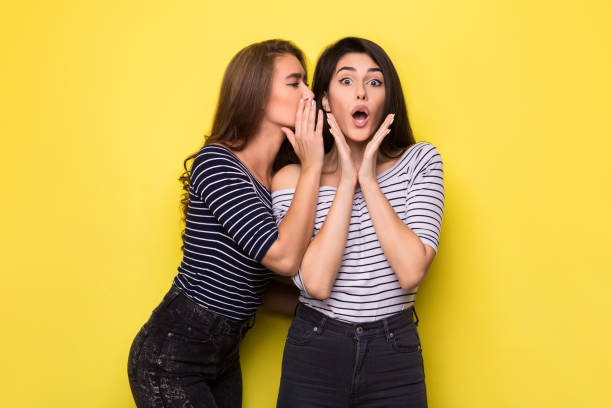 istock Two beautiful girls telling each other secret 1084465656
