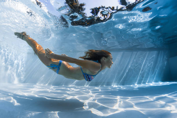 istock Young woman glides underwater 1084473082