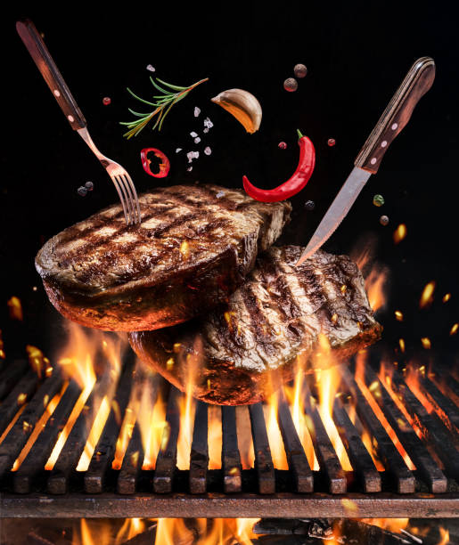 istock Beef steaks with spices fly over the blazing grill barbecue fire. 1084473894