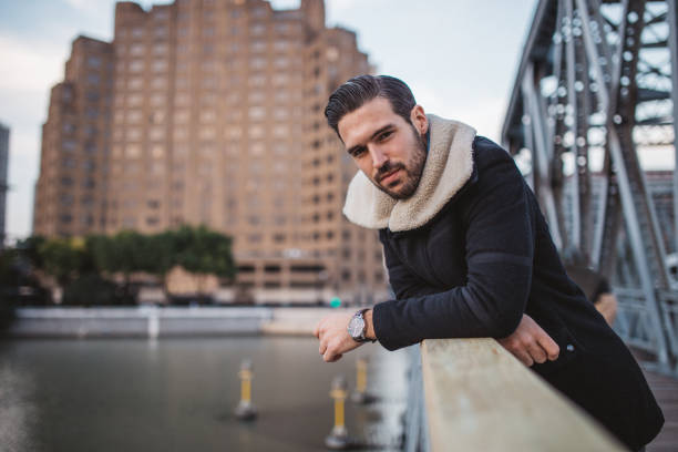 One young hipster standing on the bridge, with the city view behind