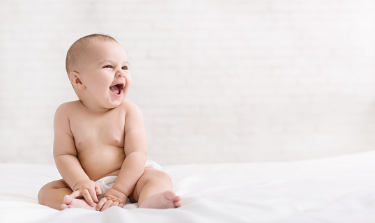 Adorable excited six month baby laughing and looking at copy space on white