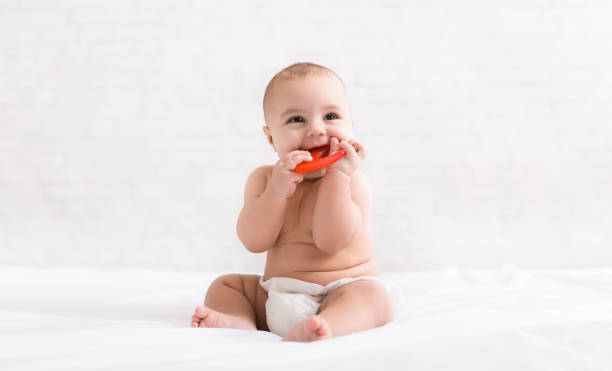 neugeborenes baby beißen rote beißring im bett - gezahnt fotos stock-fotos und bilder