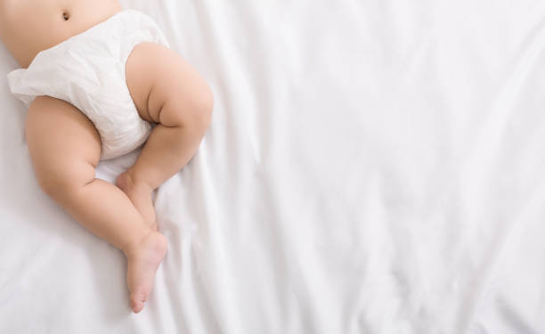 istock Baby legs and bottom in diaper on bed 1084486344