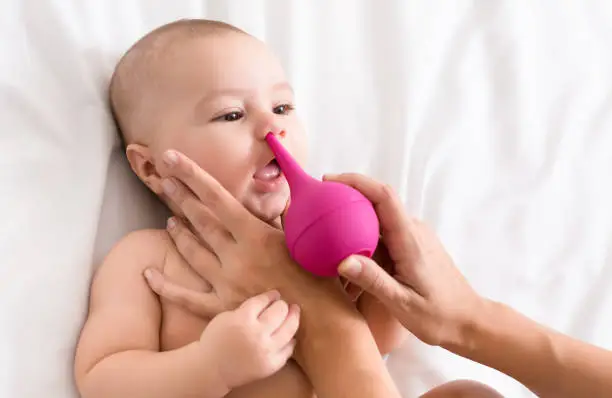 Photo of Newborn baby getting nose cleaning with cleaner